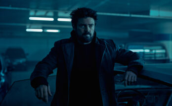 Butcher (Karl Urban) stands leaning against a car door